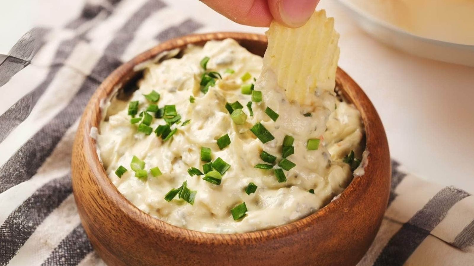 A bowl of chip dip garnished with chopped green onions.