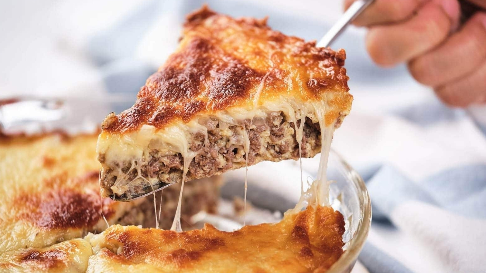 A slice of cheeseburger pie being lifted, showing layers of meat and melted cheese.