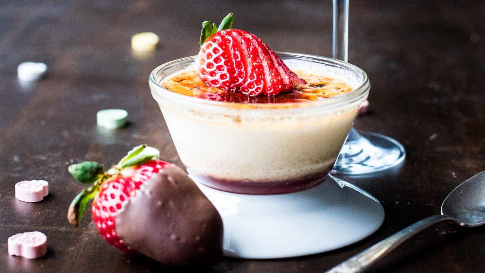 Close up of strawberry crème brûlée next to a glass of champagne.