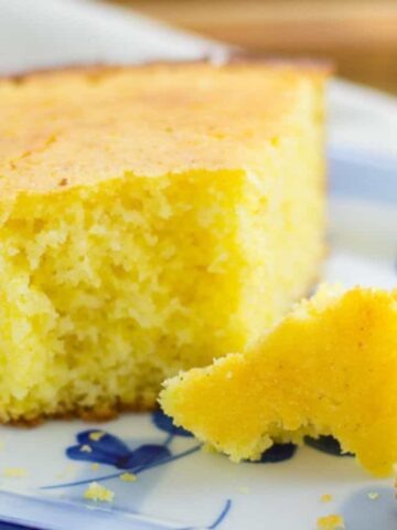 Overhead shot of cornbread in a cast iron skillet with a single slice cut out.