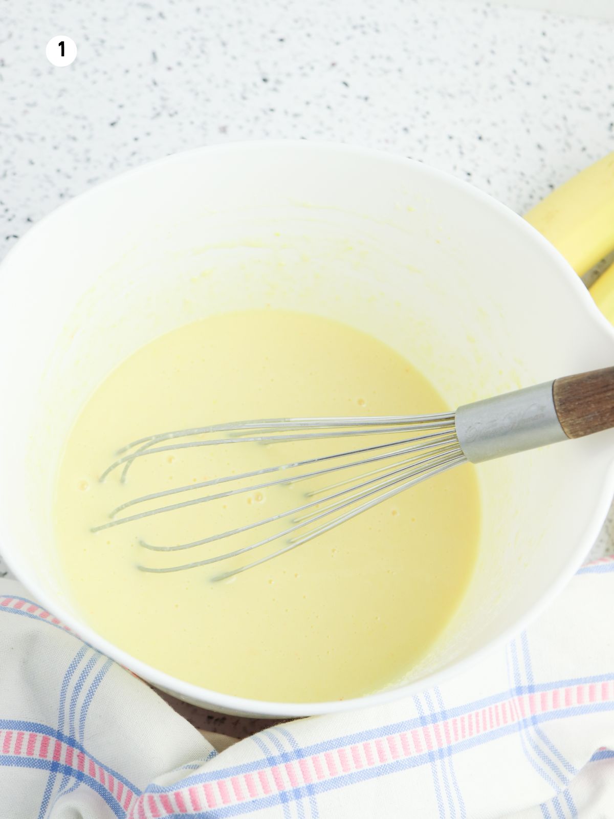 Whisking vanilla pudding mixture in a white bowl for banana pudding parfaits.
