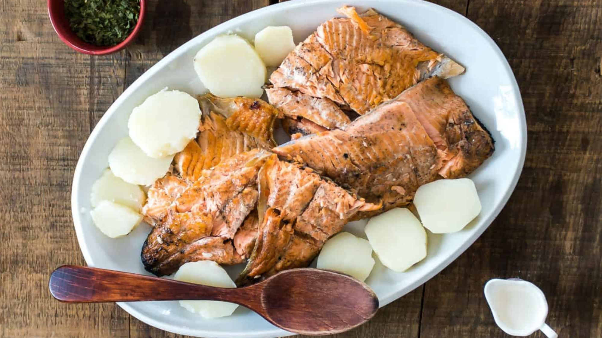 Overhead view of fire-grilled salmon in white plate.