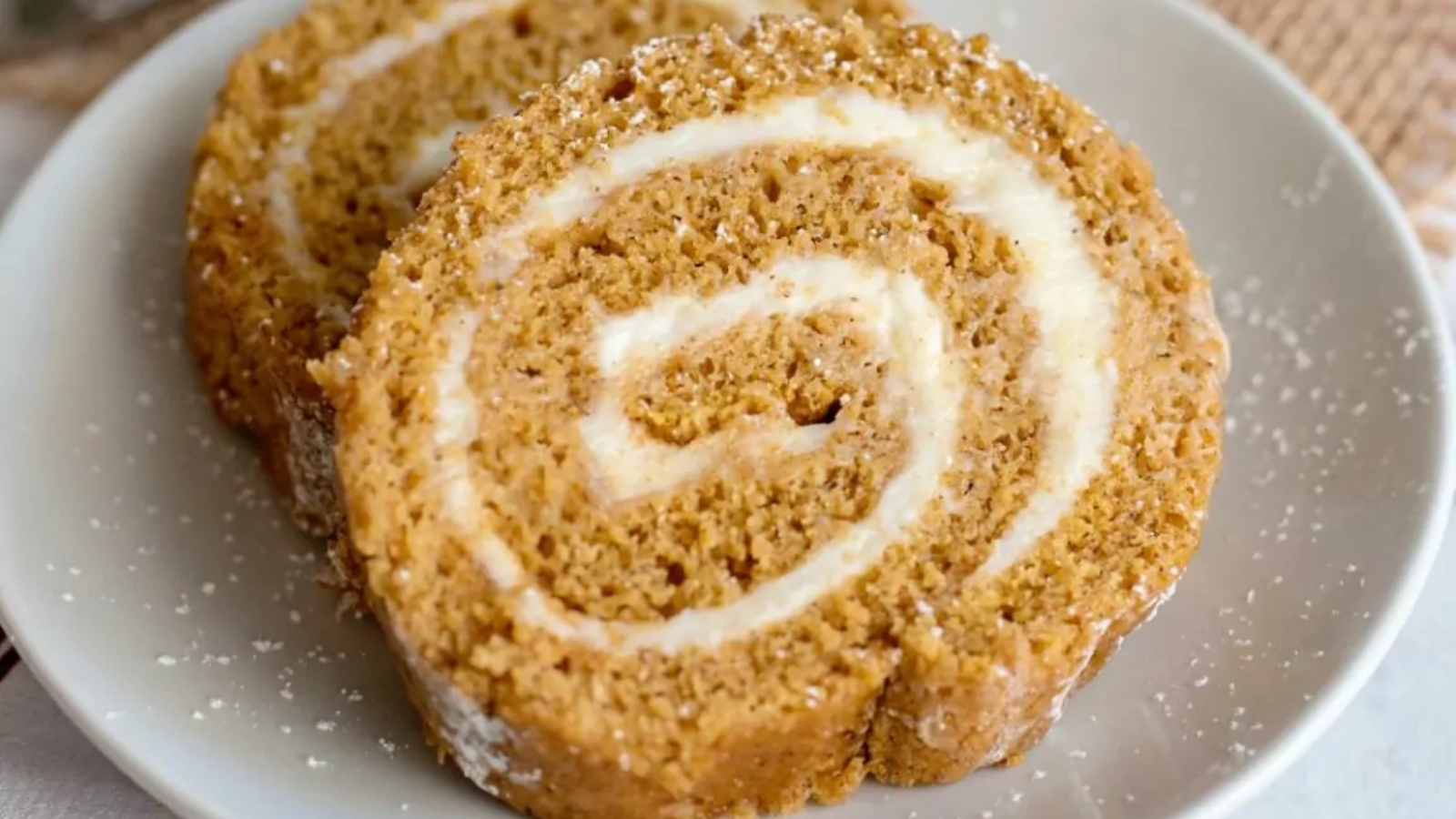 Slices of pumpkin roll served on a white platter.