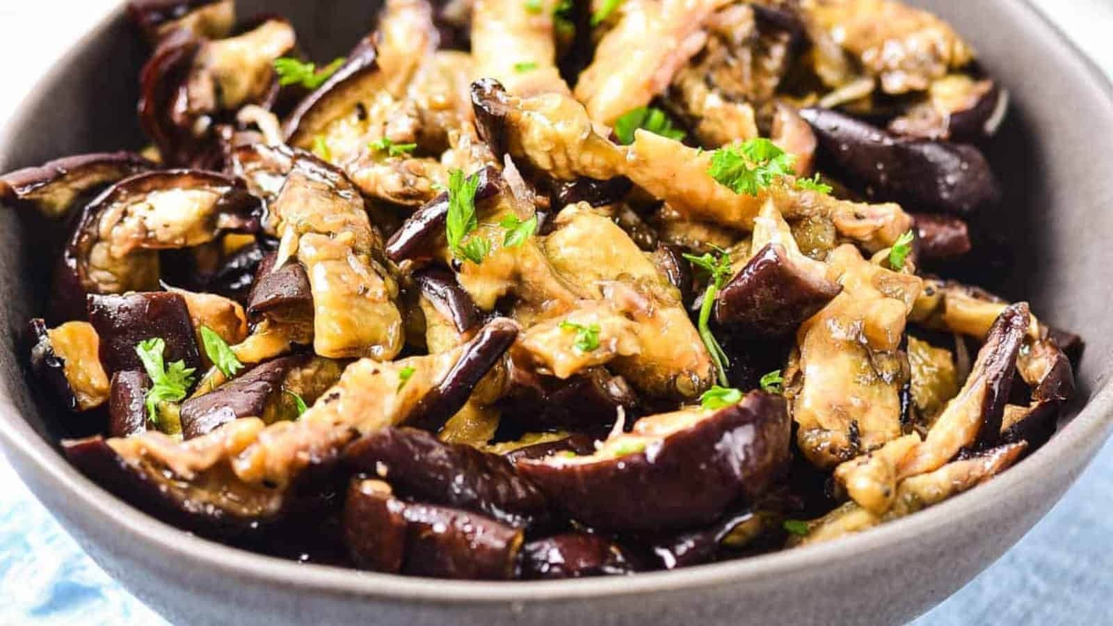 A bowl of pickled eggplant slices with garlic and spices.