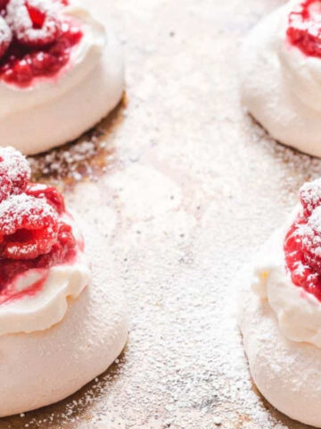 A few raspberry pavlovas on a baking sheet.
