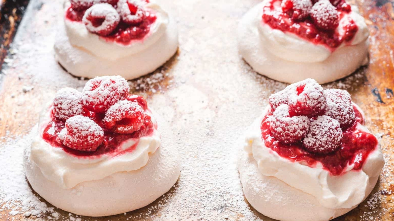A few raspberry pavlovas on a baking sheet.