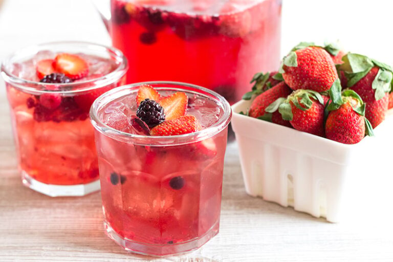 Red Berry Pomegranate in 2 glasses and a small container of fresh strawberries.