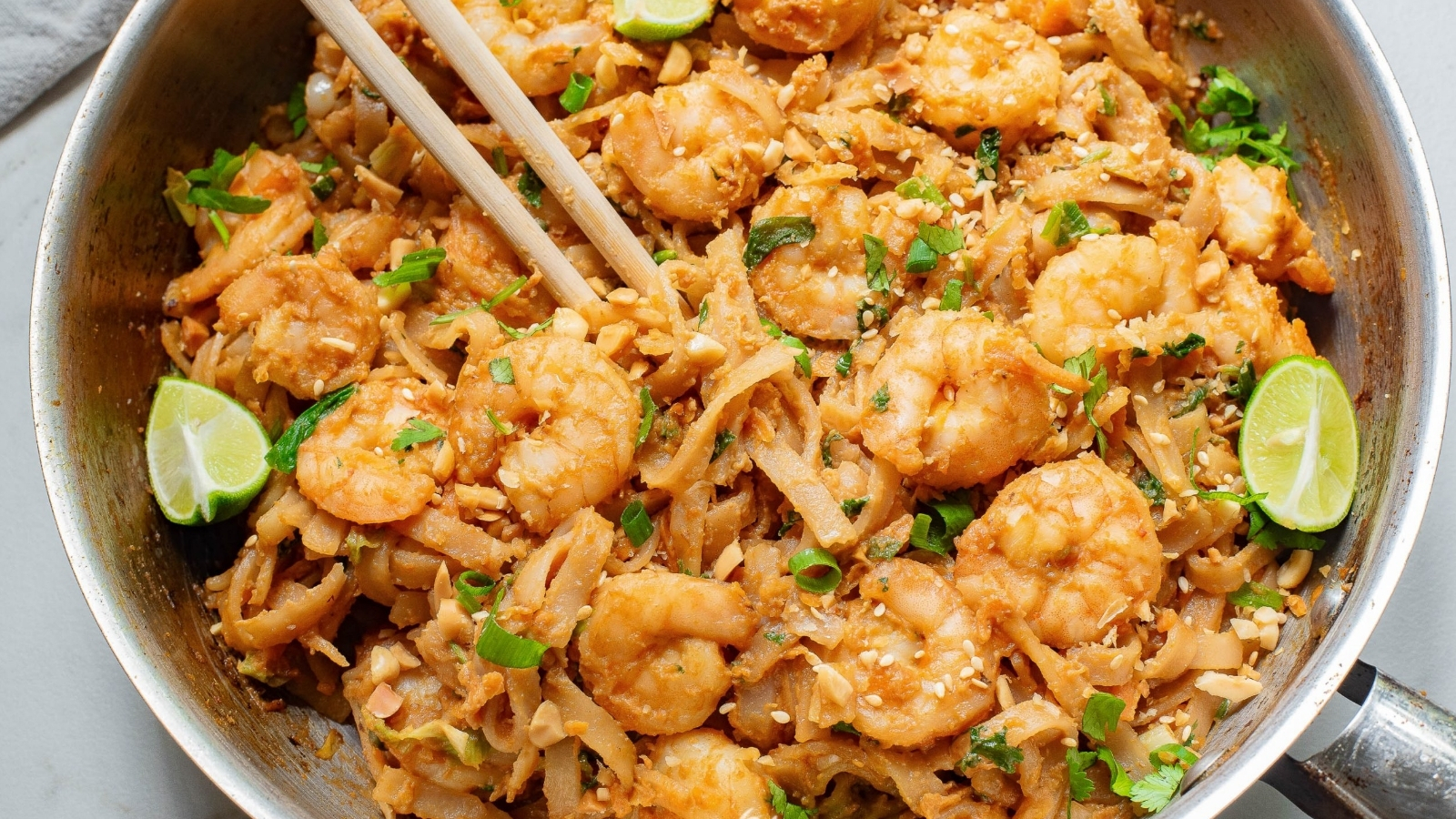 A pan full of shrimp and noodles with chopsticks.