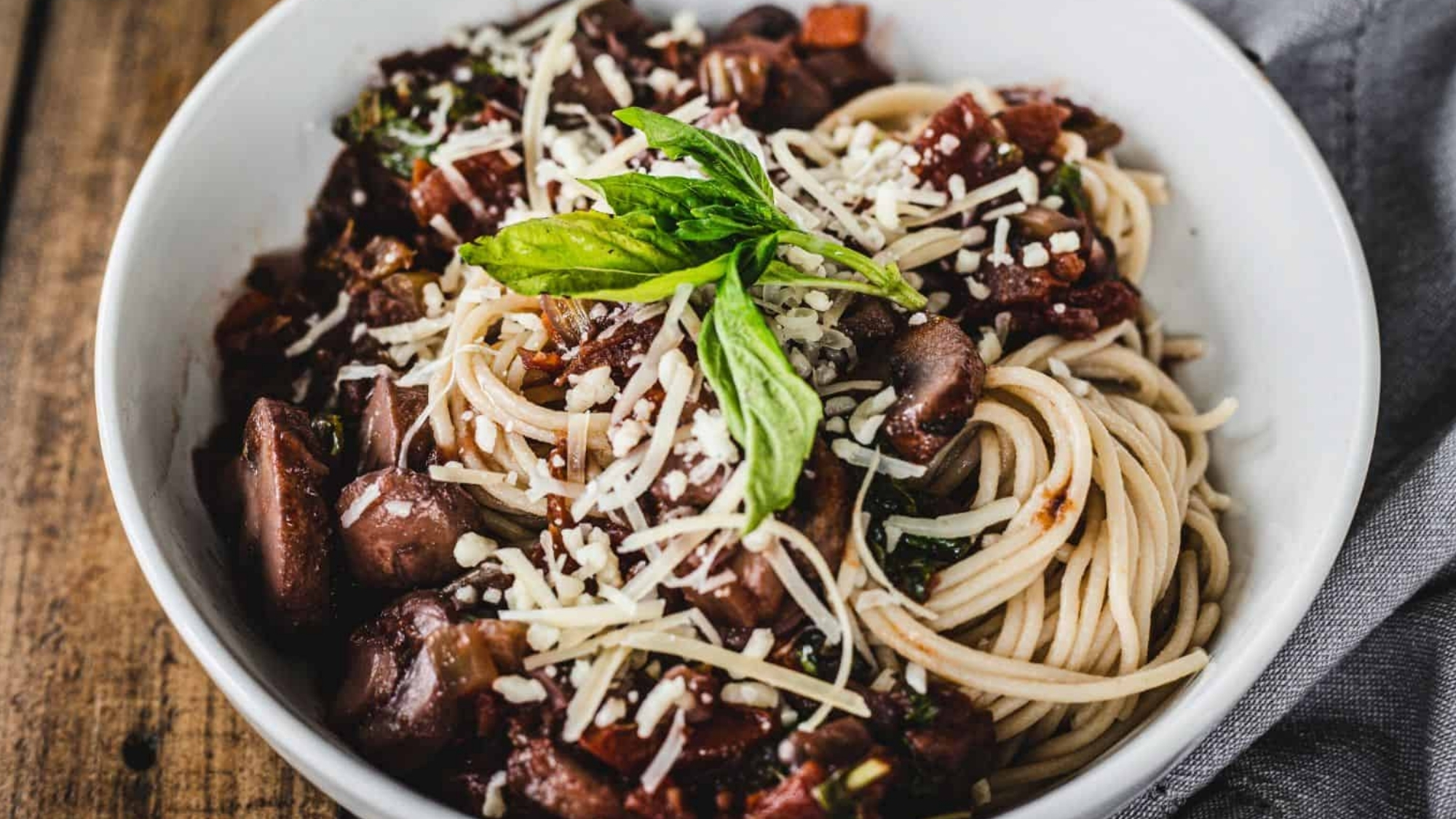A close up of spaghetti with meat and basil.