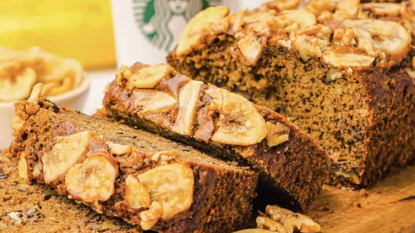 Sliced banana bread topped with banana chips and walnuts, with a Starbucks cup in the background.