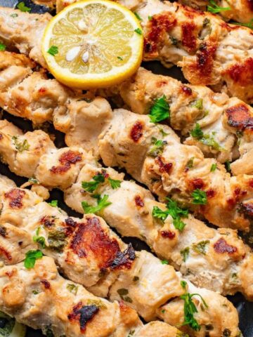 Chicken skewers with lemon wedges on skewers.