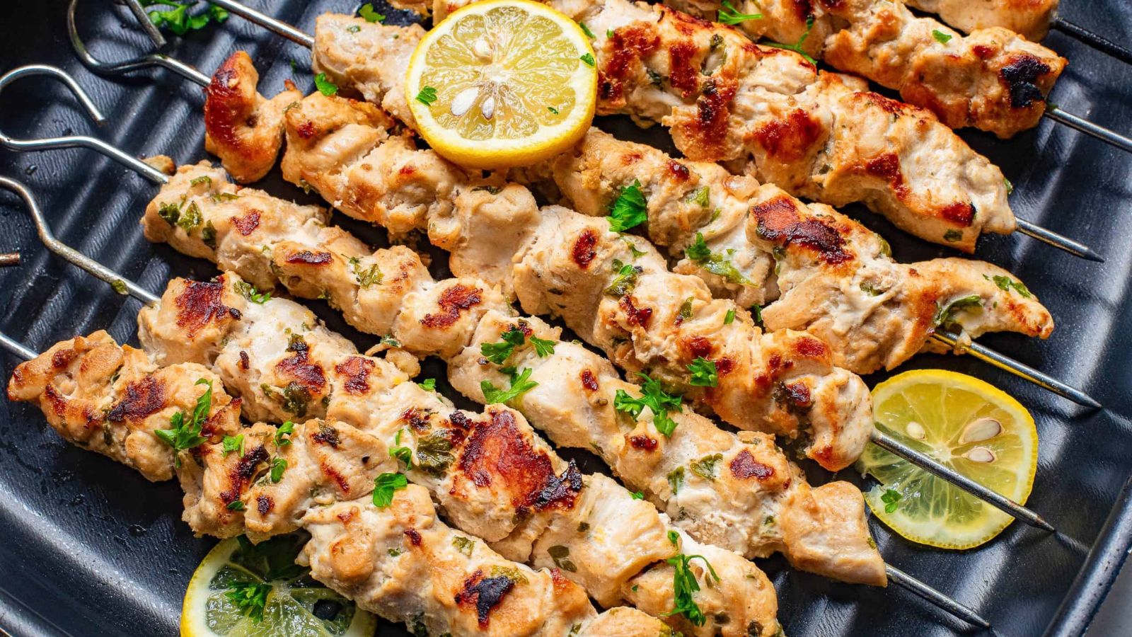 Chicken skewers with lemon wedges on skewers.