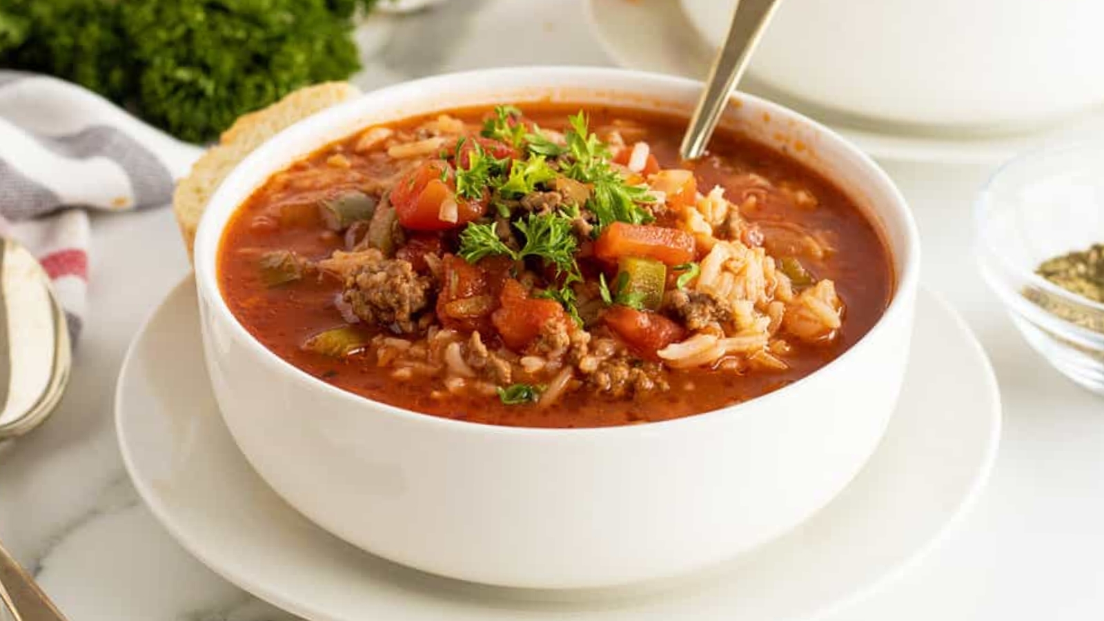 A bowl of hearty stuffed pepper soup with chunks of beef, rice, and colorful bell peppers in a rich tomato broth.