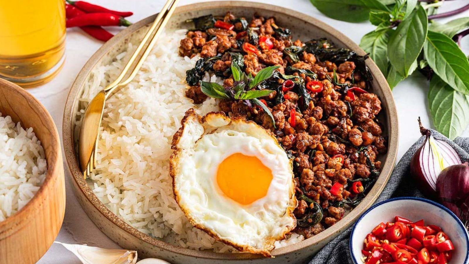 A bowl of ground pork topped with fresh basil leaves.