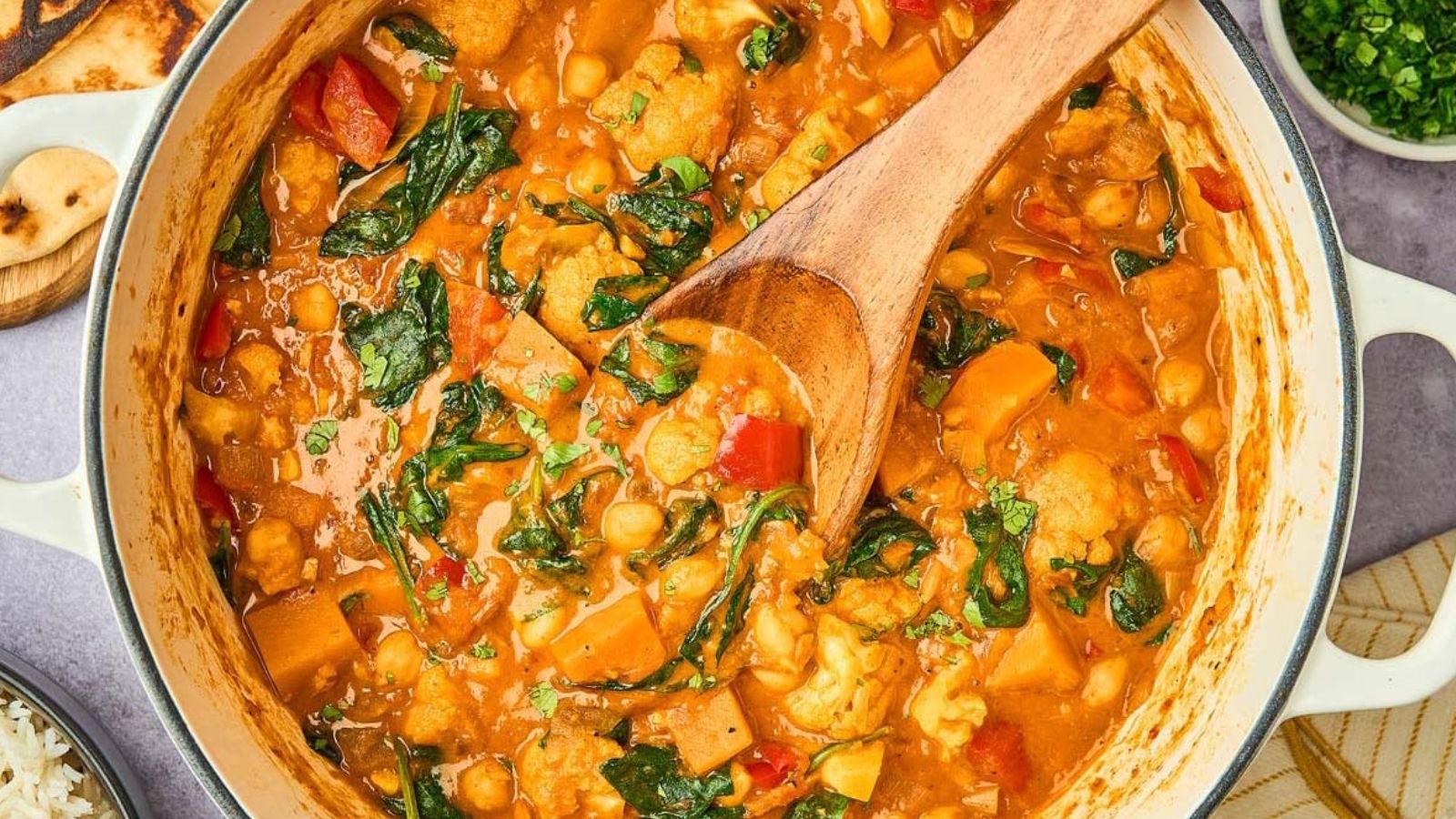 Vegetable curry with chickpeas, cauliflower, spinach, and red peppers in a creamy orange-colored sauce.