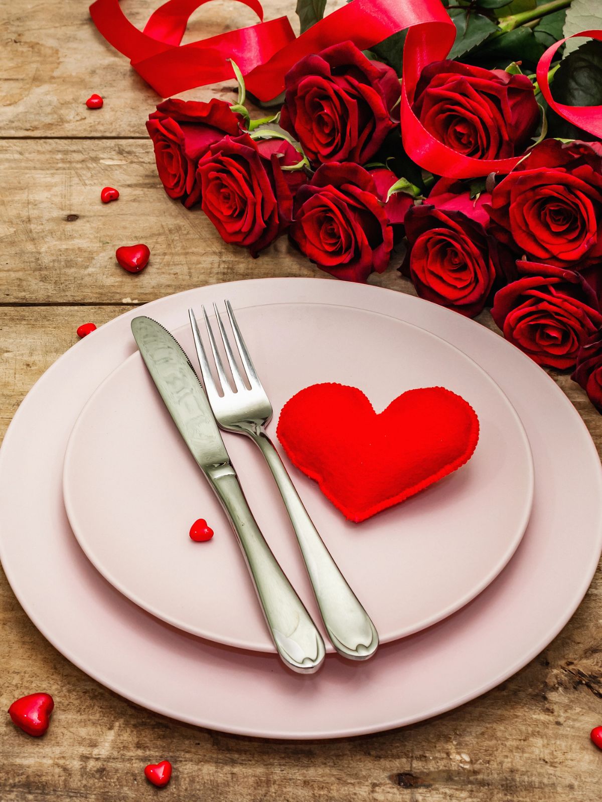 Valentine's Day Menu Perfect for Two - let's skip the restaurant and enjoy a delicious romantic meal at home with the love of your life from Walking on Sunshine Recipes. pink plates set for dinner with fabric heart and roses in the background.