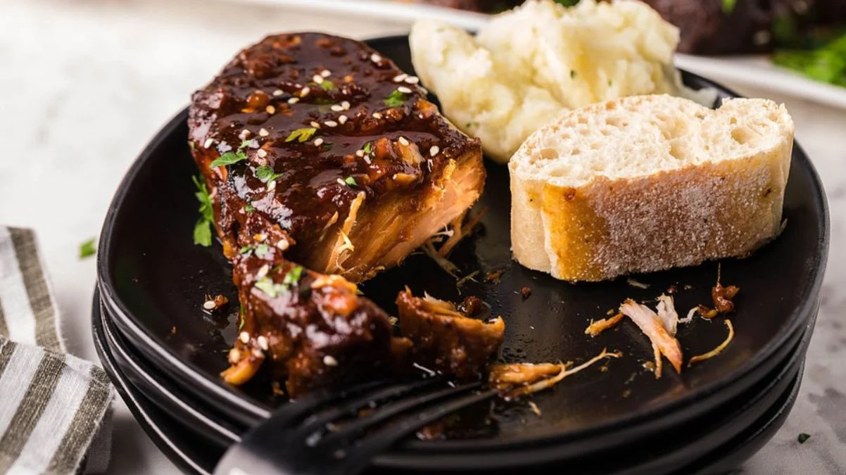 Pork chops cooked in a slow cooker with a sweet and spicy sauce made from sriracha, honey, and garlic.