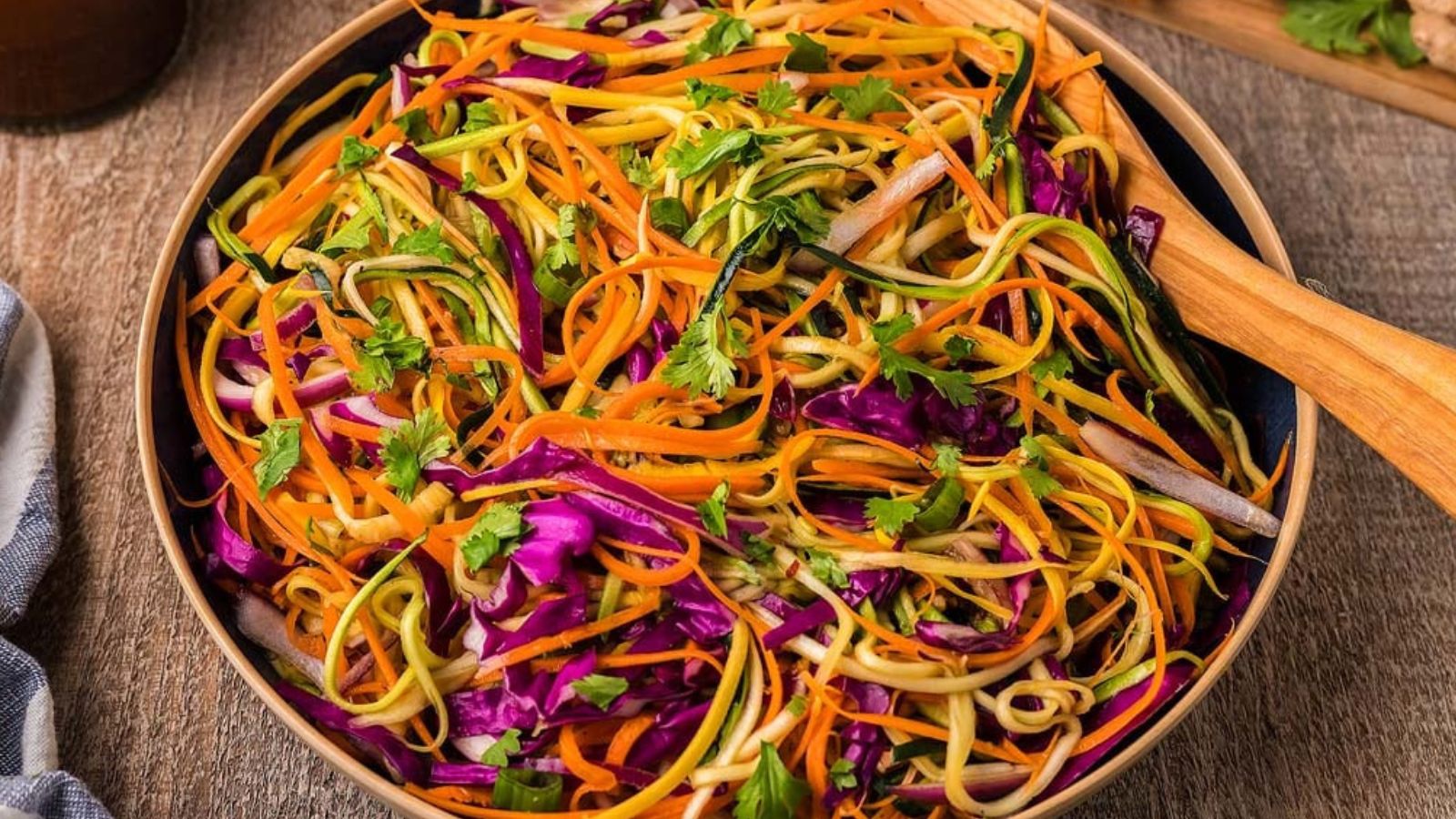 A bowl of spiralized zucchini noodles mixed with sliced vegetables and garnished with herbs.