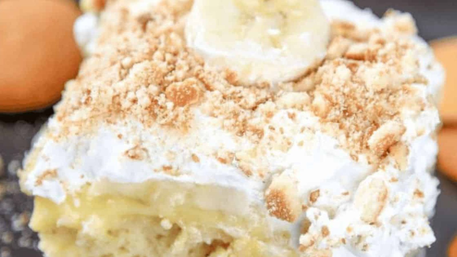A slice of banana pudding cake topped with sliced bananas and crushed vanilla wafers.