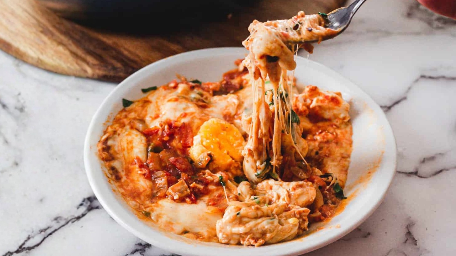 A person scooping a dish of eggs in a skillet.