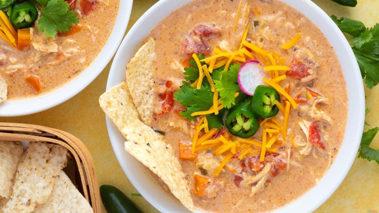 Slow cooker chicken tortilla soup topped with cheese and tortilla chips.