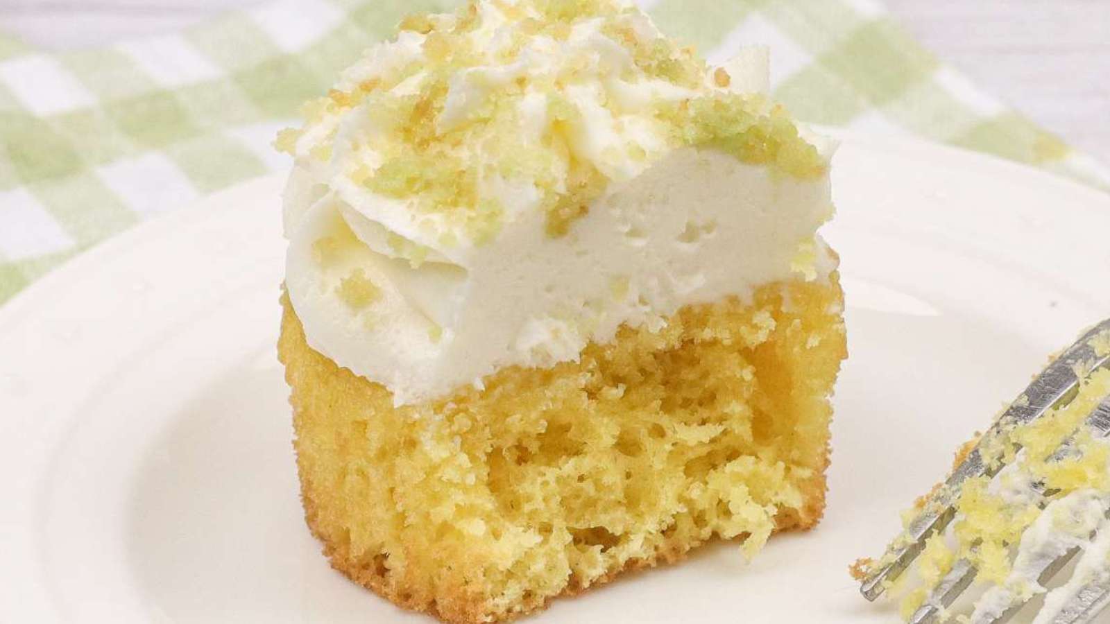 A piece of coconut cupcake with white lime frosting.