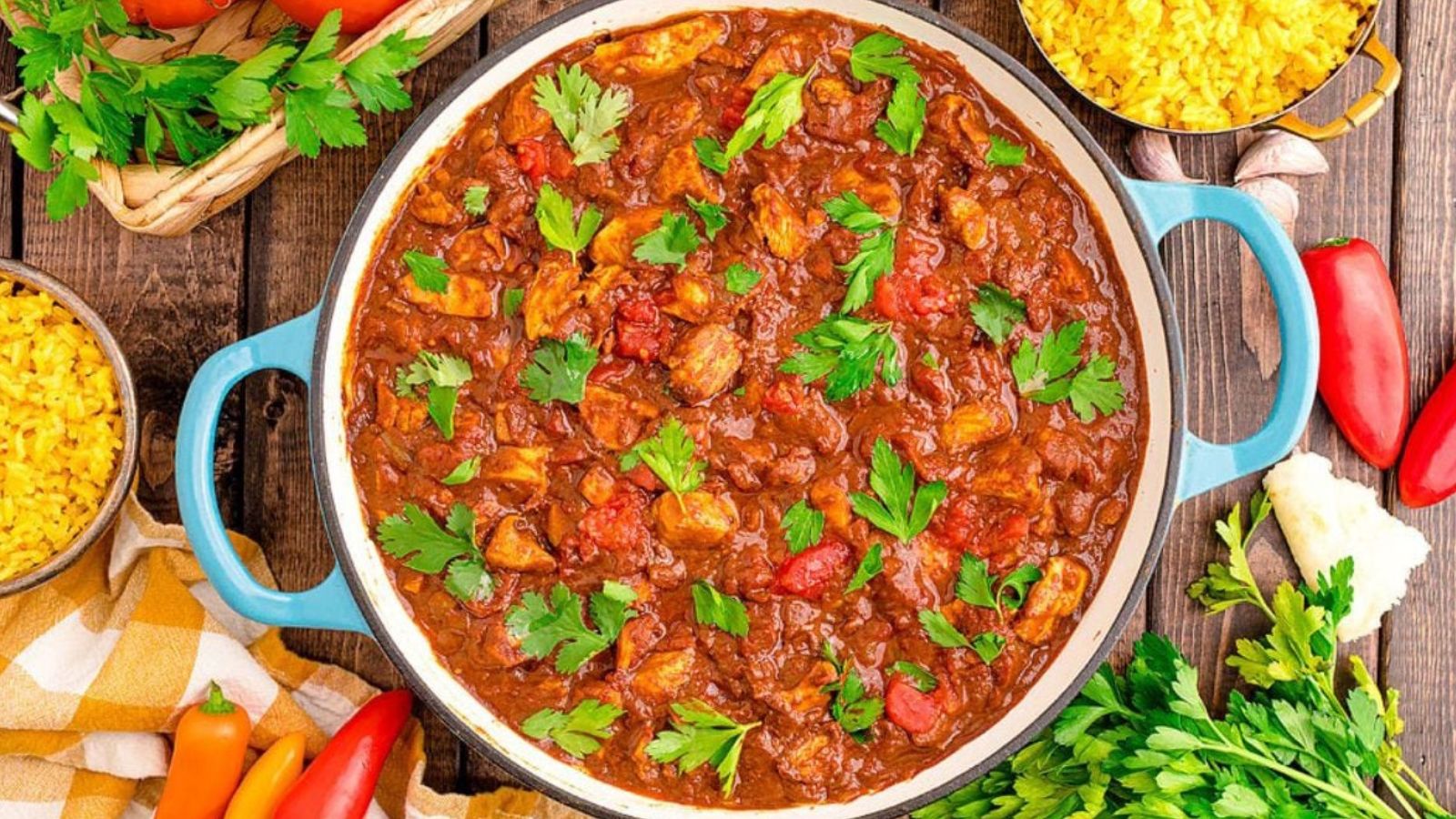 A pot of chicken pieces in a reddish curry sauce.