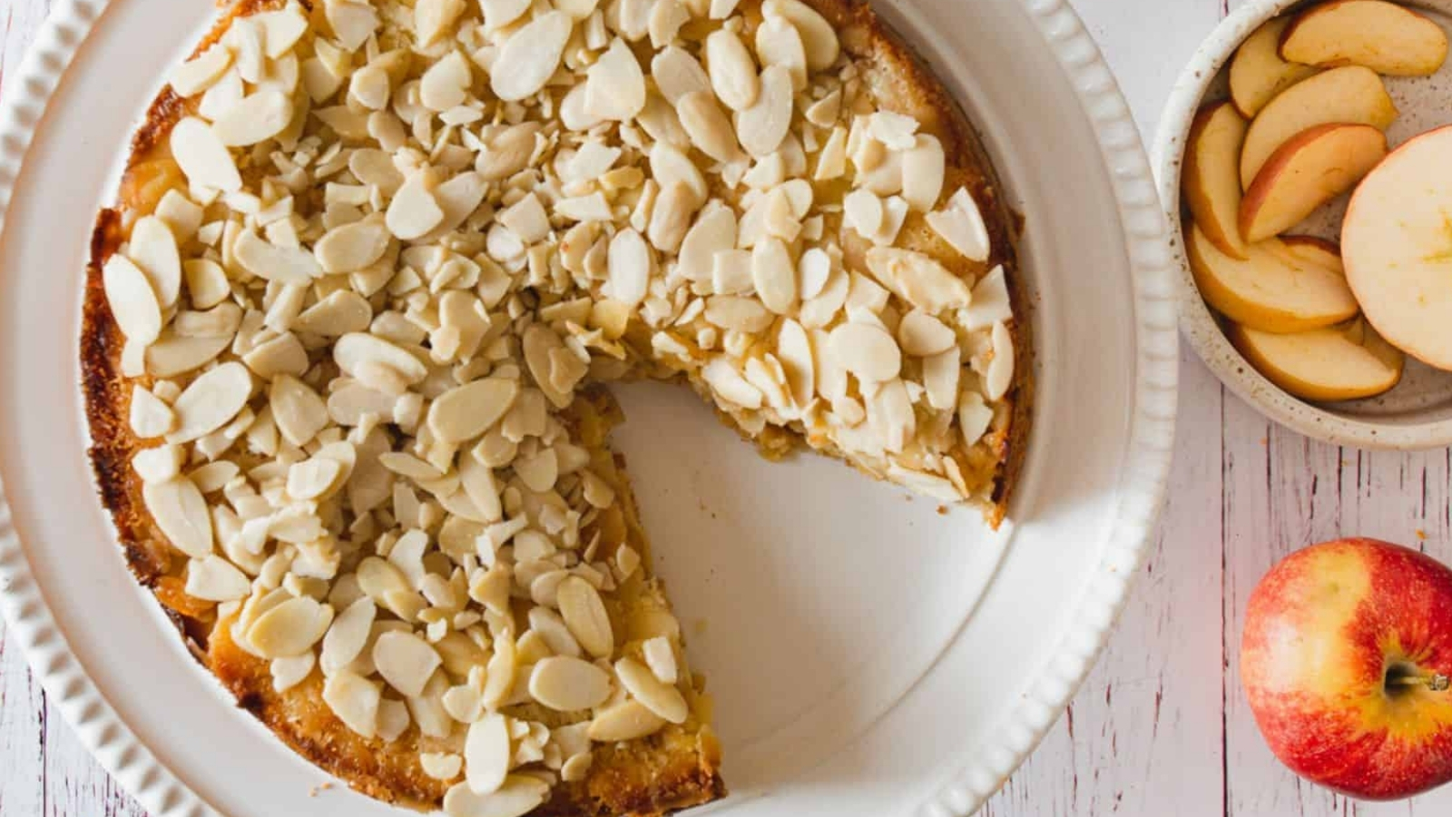 A plate of apple pie with a slice taken out of it.