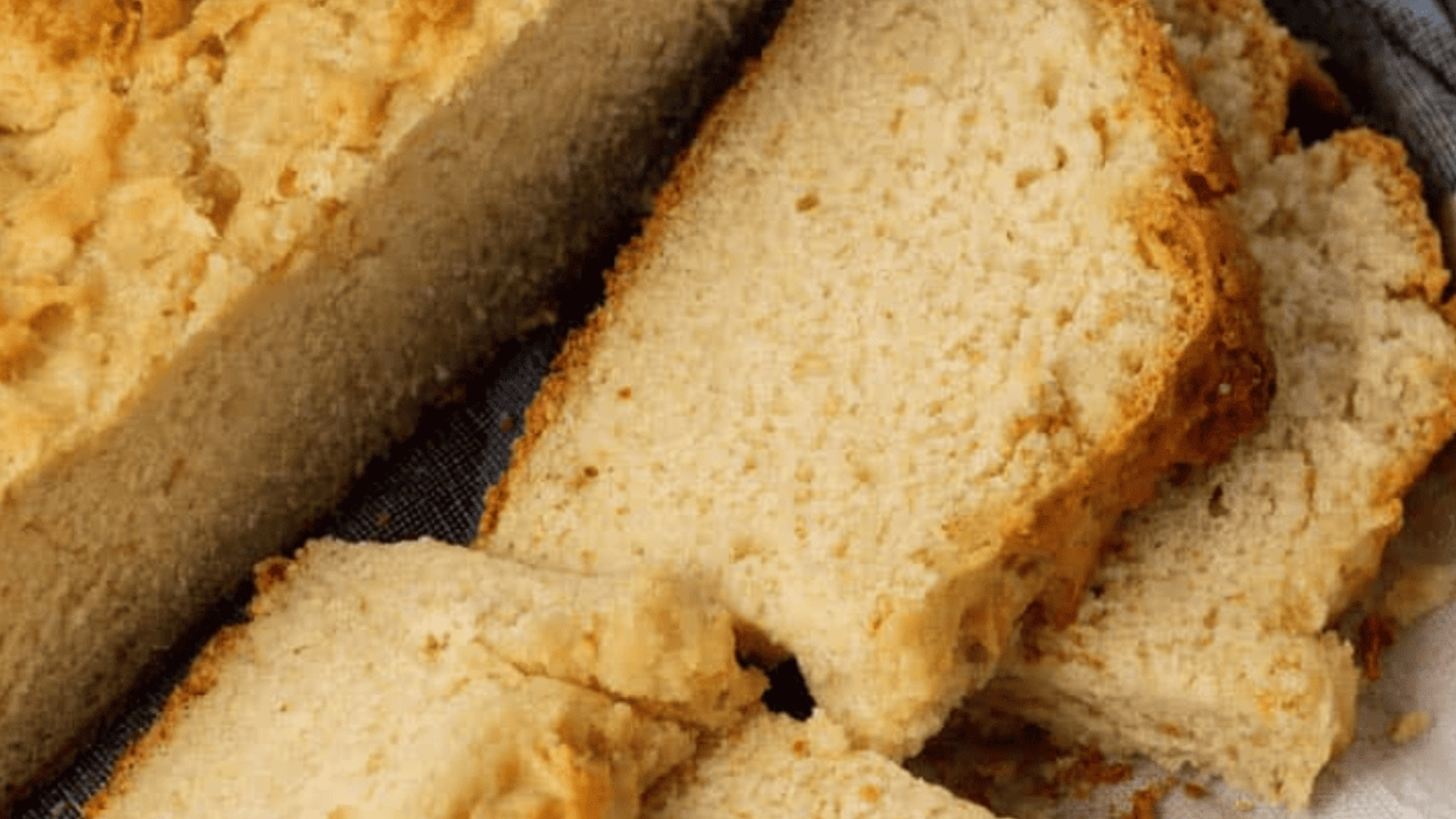 Loaf of Irish soda bread on a wooden board with a few slices cut.