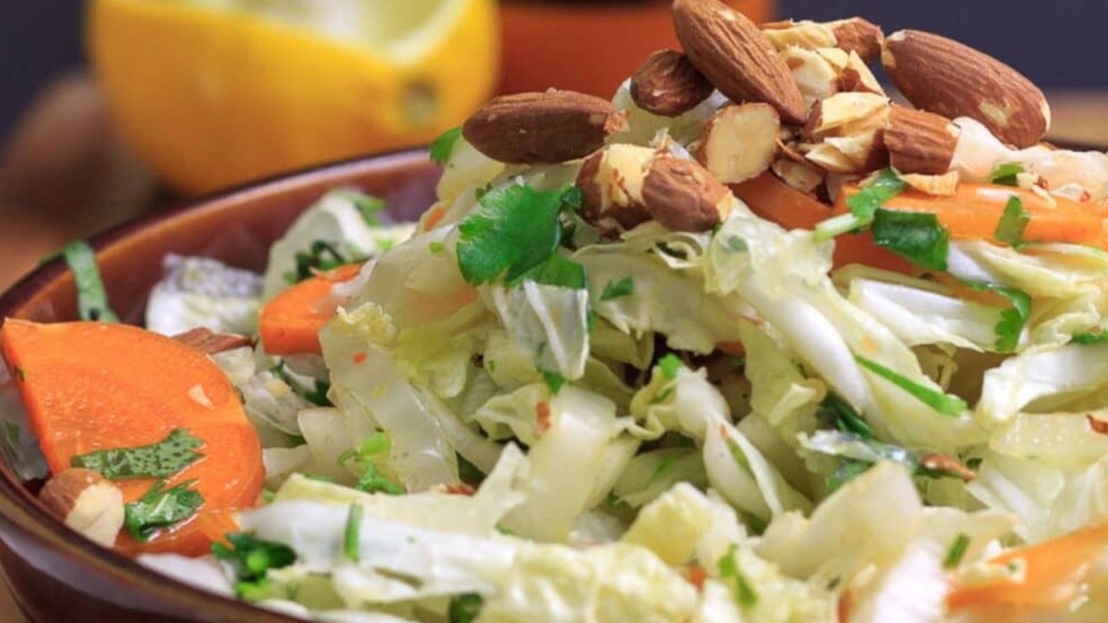 Shredded cabbage mixed with thin carrot strips, sliced onion, and herbs in a bowl.