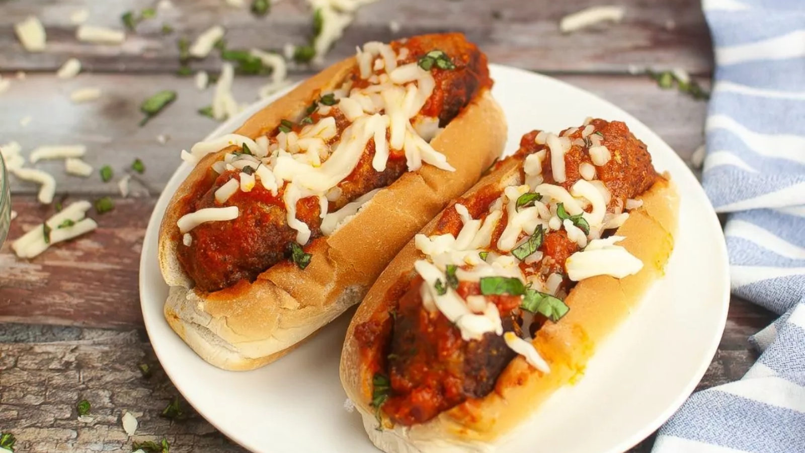 Meatball sandwich on a toasted roll filled with saucy meatballs and melted cheese, served on a plate.