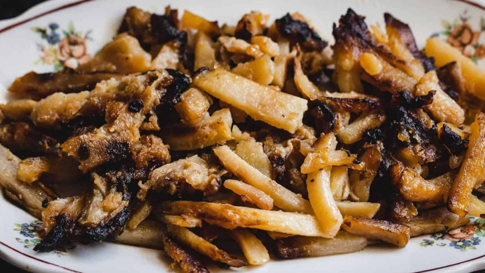 A plate of fried, golden-brown pork trimmings on a floral-patterned dish.
