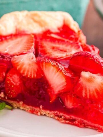 Strawberry pie with a glossy red filling and sliced strawberries arranged on top in a pie crust.