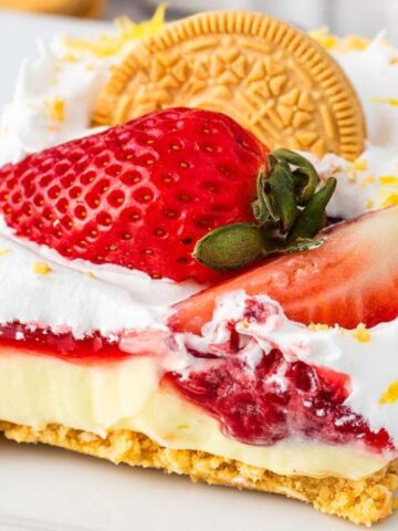 Layers of strawberry and lemon dessert with cream and graham cracker crumbs in a glass dish.