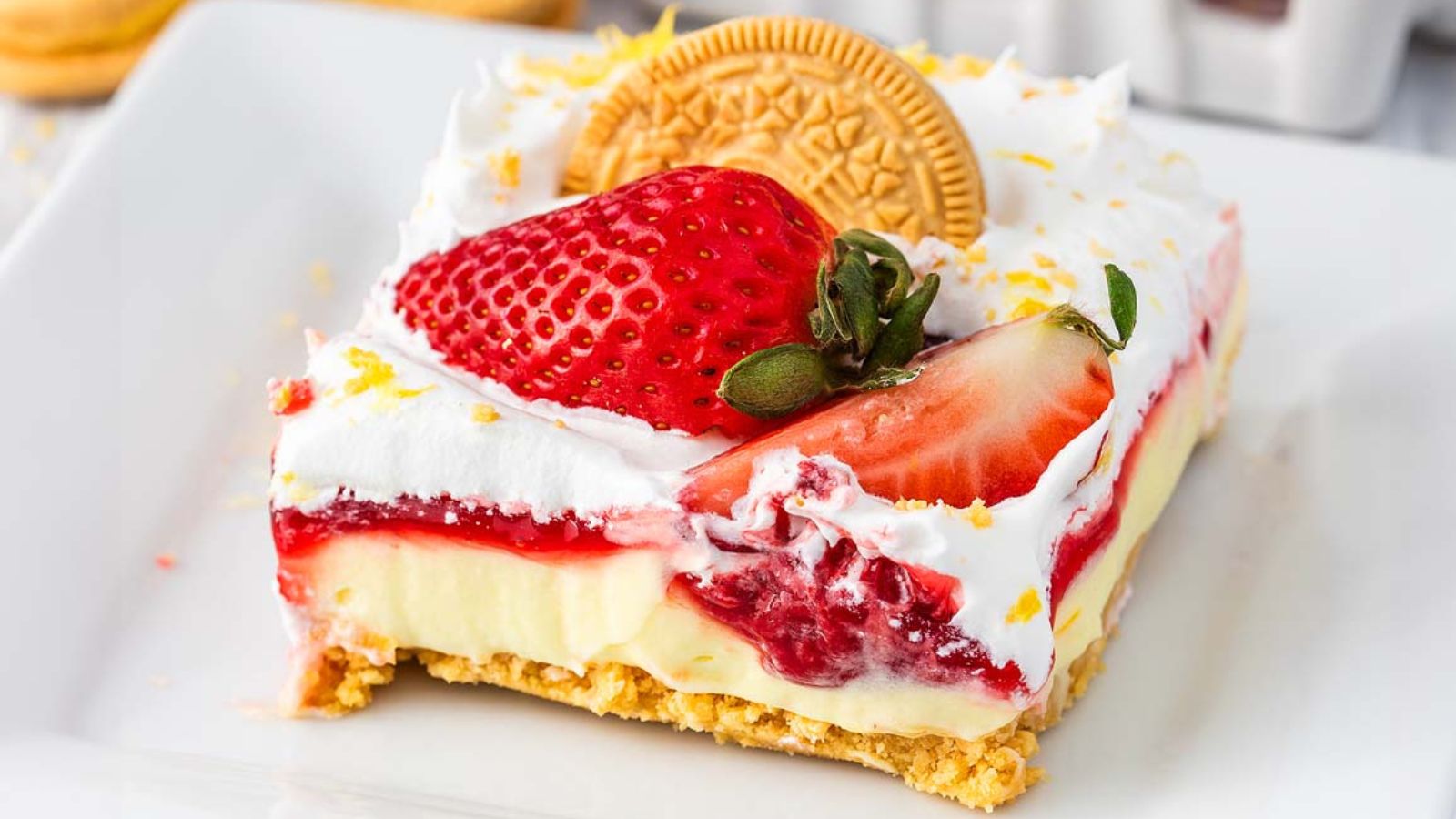Layers of strawberry and lemon dessert with cream and graham cracker crumbs in a glass dish.