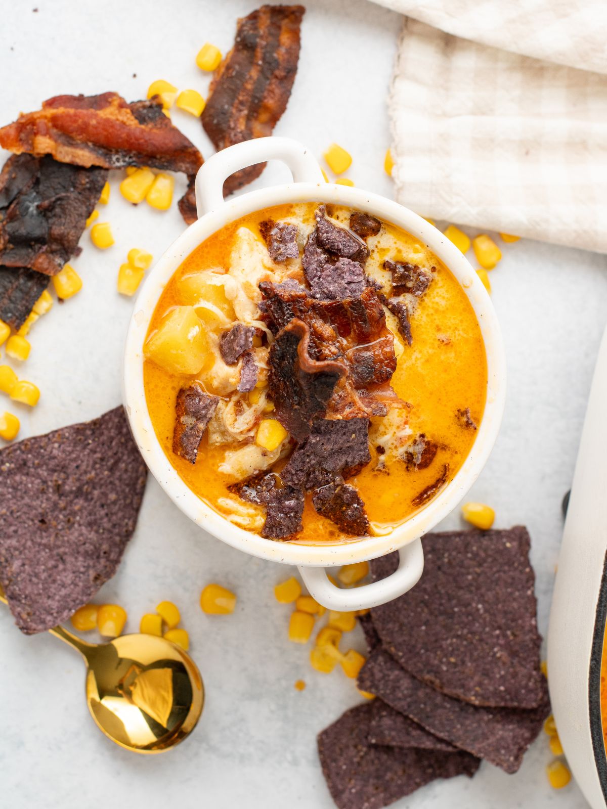 corn chowder soup with chicken, bacon and tortilla chips in white bowl.