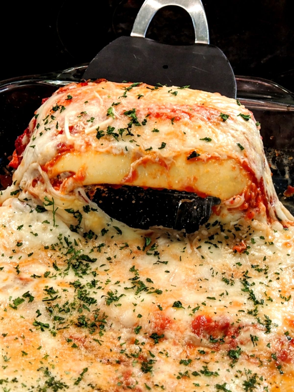 homemade manicotti with crepes in casserole dish with spatula.