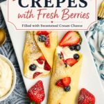 Pinterest graphic for dessert crepes with fresh berries and sweetened cream cheese filling on a white serving platter topped with powdered sugar and strawberries.