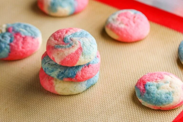 Baked stacked red, white and blue swirl cookies and single cookies on cookie baking sheet.
