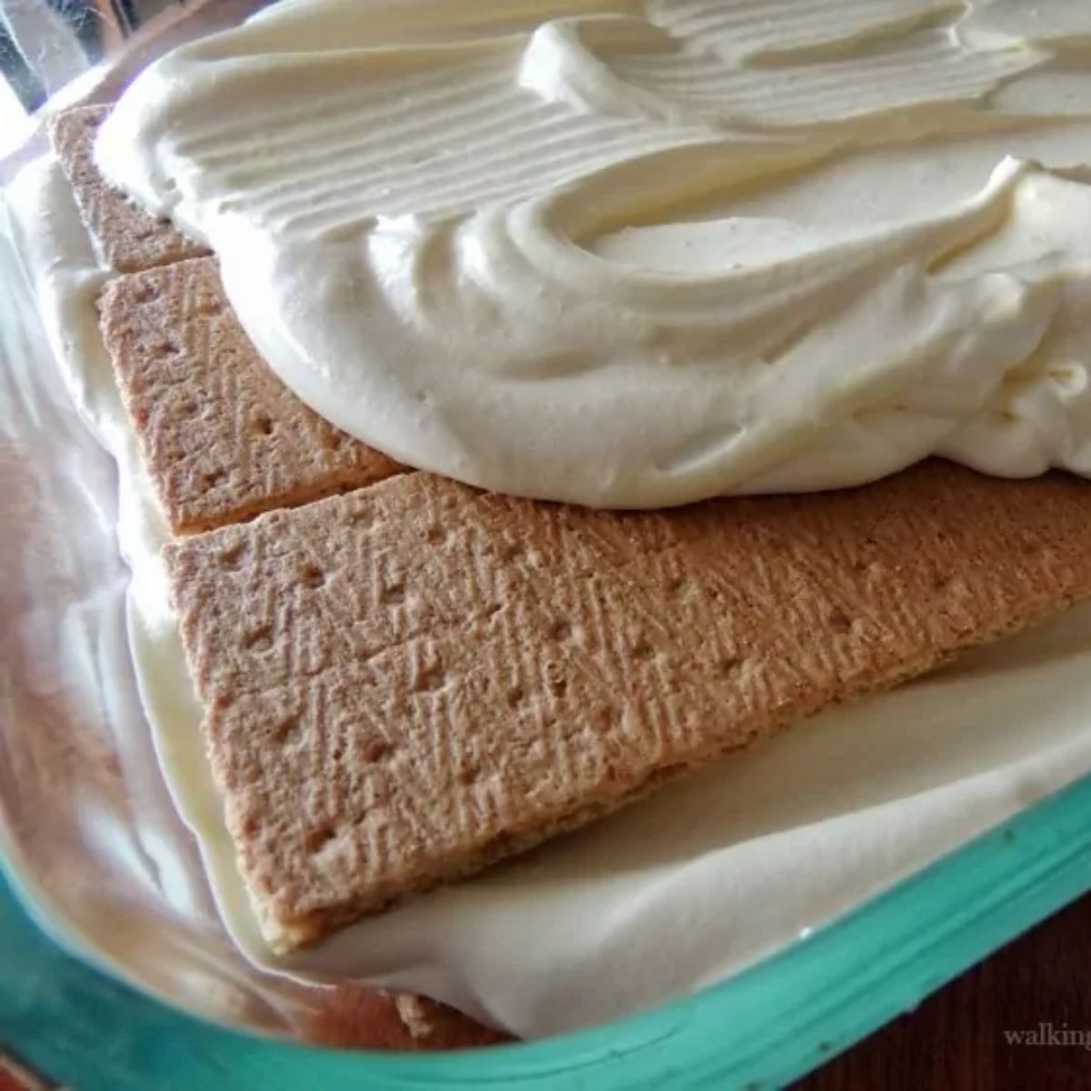 Vanilla pudding layered over graham crackers in a glass baking dish for no bake chocolate eclair pie.
