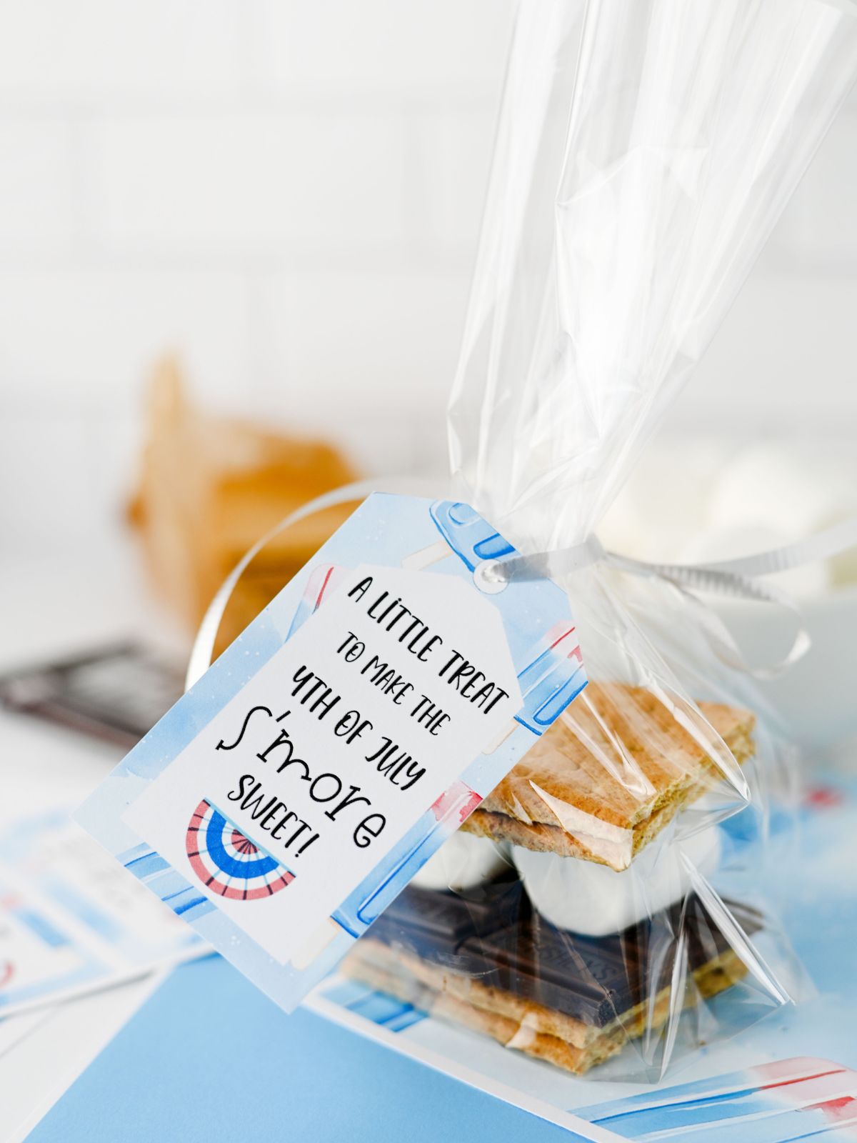 S’mores to go treat bag with graham crackers, chocolate, and marshmallows and a printable gift tag.