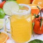 Refreshing orange juice mocktail served over ice with a lime garnish and salted rim.