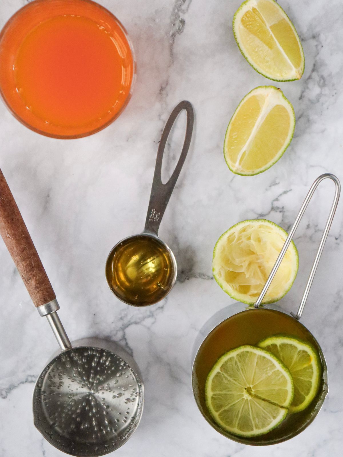 Ingredients for an orange juice mocktail recipe including orange juice, lime juice, sparkling water, and agave syrup.