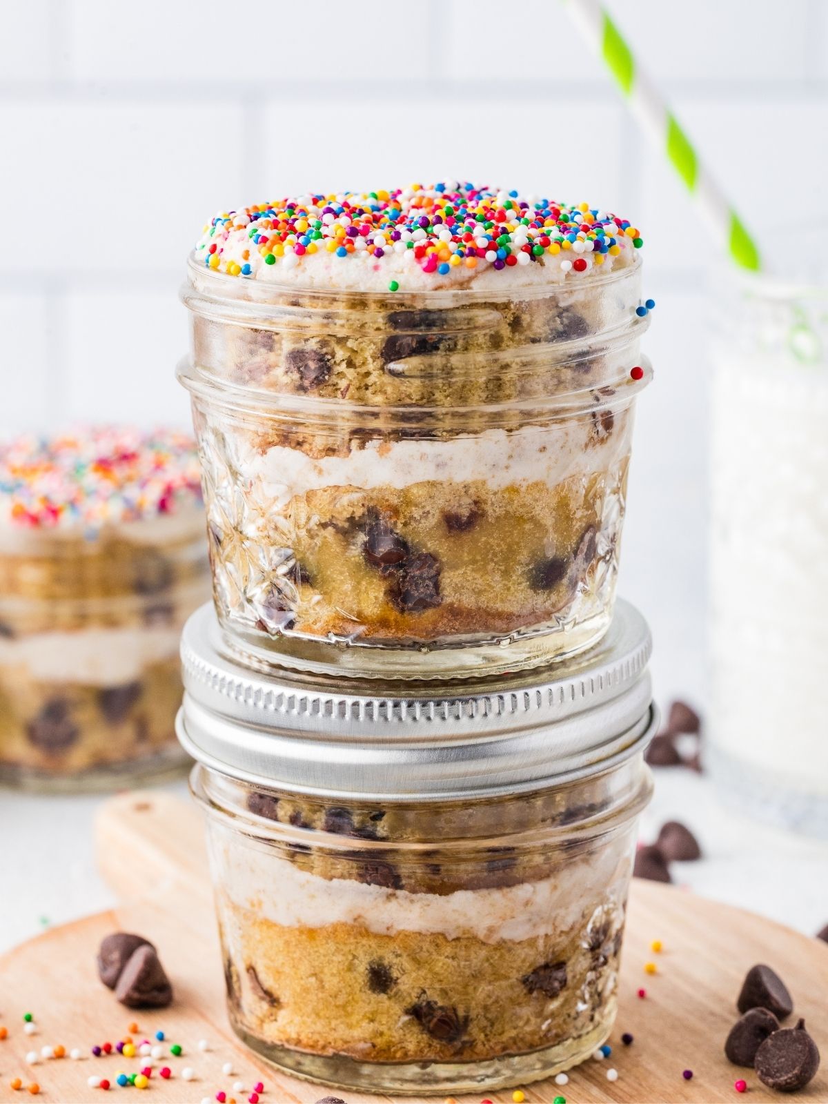Chocolate chip cake layered with frosting in mason jars and topped with rainbow sprinkles.