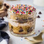 Mason Jar Chocolate Chip Dot Cake layered with frosting, chocolate chips, and rainbow sprinkles in an individual glass jar.