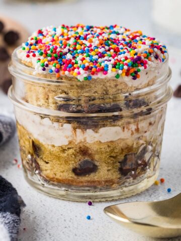 Mason Jar Chocolate Chip Dot Cake layered with frosting, chocolate chips, and rainbow sprinkles in an individual glass jar.