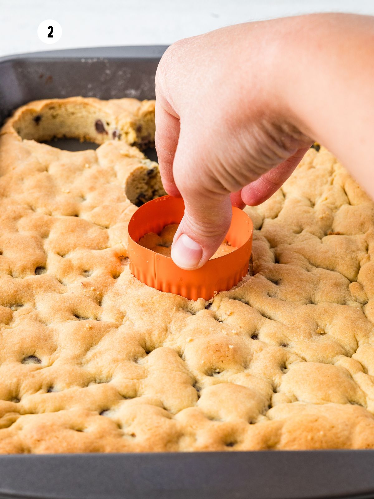 Using a round biscuit cutter to cut circles from baked chocolate chip cake for layering in mason jars.
