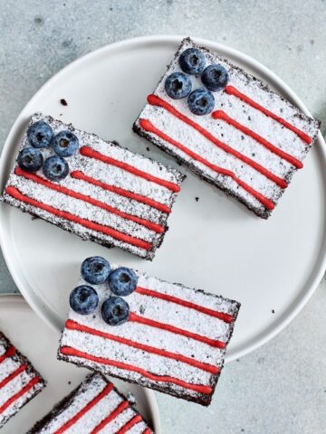 Overhead view of American Flag Brownies decorated with powdered sugar, blueberries, and red icing.
