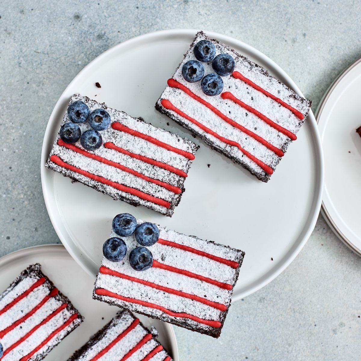 Overhead view of American Flag Brownies decorated with powdered sugar, blueberries, and red icing.