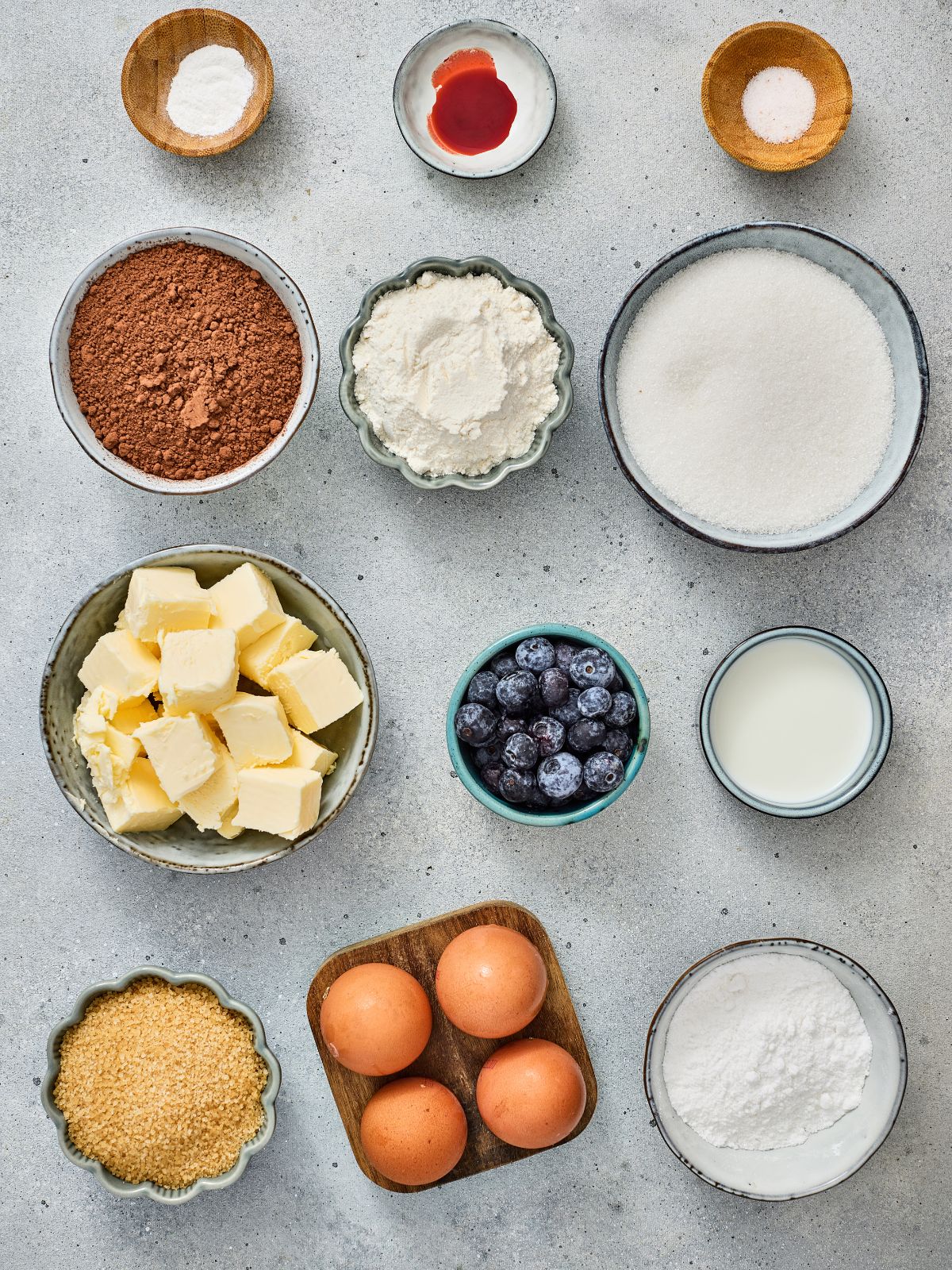 Ingredients needed to make American Flag Brownies, including cocoa powder, butter, eggs, blueberries, powdered sugar, and red icing.